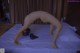 A naked woman doing a handstand on a bed.