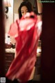 A woman in a red dress standing in front of a mirror.