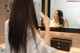 A woman brushing her hair in front of a mirror.