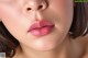 A close up of a woman's face with pink lipstick.