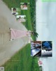 A woman in a pink dress standing on a dirt road.