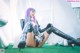 A woman with purple hair sitting on the grass.