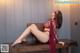 A woman in a red lingerie sitting on a table.