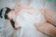 A woman laying on a bed wearing a white lingerie.