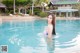 A woman in a pink bikini standing in a pool.