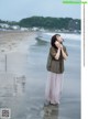 A woman standing on a beach next to the ocean.