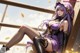 A woman in a purple outfit sitting on a wooden railing.