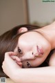 A woman laying on a bed with her head resting on her hand.